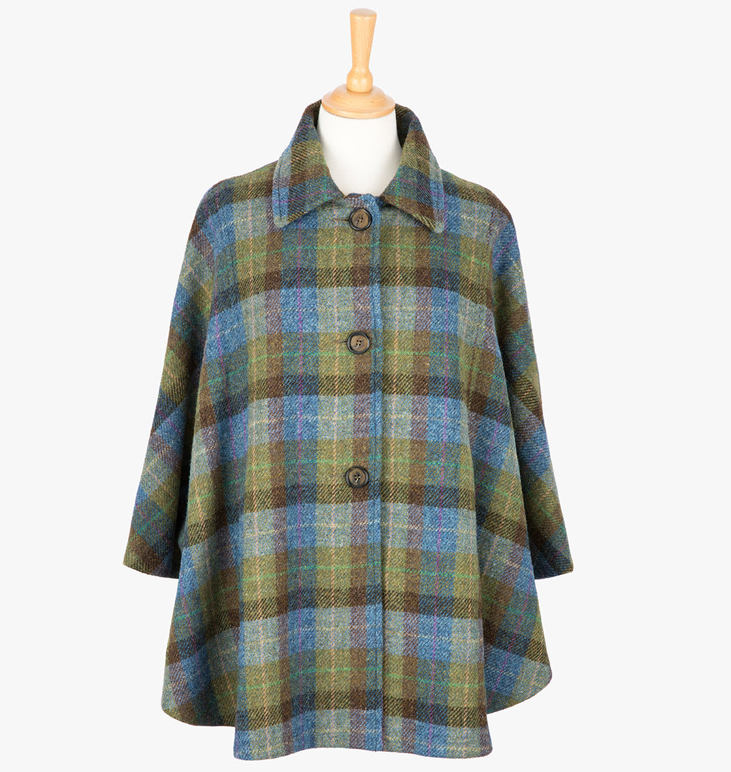 This is the Harris Tweed cape in denim sage, the colour is blue, brown and green check. It has 3 buttons and a collar that can be worn both up and down. It has buttons at the side which hold the cape together to give it more structure. This cape has two pockets and is a one size fits all garment.