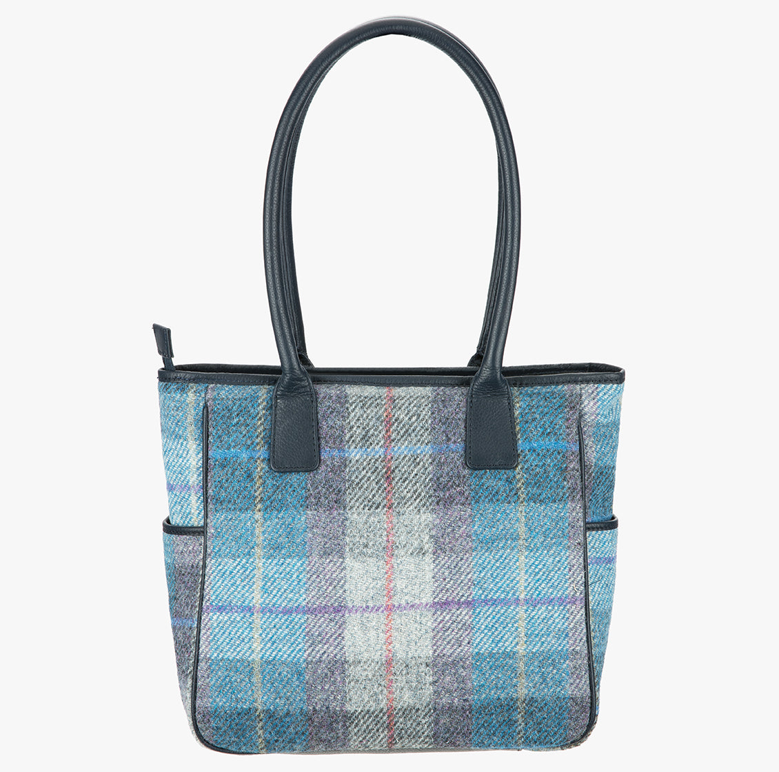 This is the reverse of the Harris Tweed tote bag in pale blue, purple and grey check with handles which go over the shoulder. This bag is Lavender Harris Tweed with navy blue leather handles. It has a pocket on each side of the bag trimmed with navy leather.