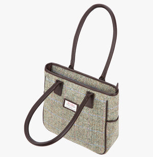Harris Tweed tote bag with handles that go over the shoulder in pastel check. This bag is a brown and cream herringbone with a pink and pale blue over check and brown leather handles. It has a pocket on each side of the bag trimmed with brown leather. This bag is shown with the front handed folded over.