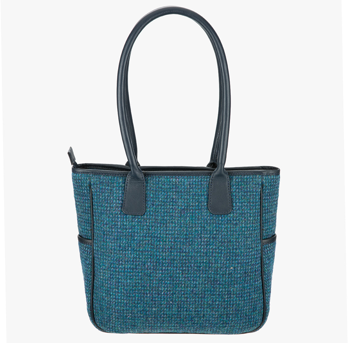 Showing the reverse of this Harris Tweed tote bag with handles that go over the shoulder. This bag is a teal Harris Tweed bag with black leather handles. It has a pocket on each side of the bag trimmed with black leather.