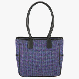 The reverse of the Harris Tweed tote bag with handles that go over the shoulder. This bag is violet harris tweed with black leather handles. It has a pocket on each side of the bag trimmed with black leather.