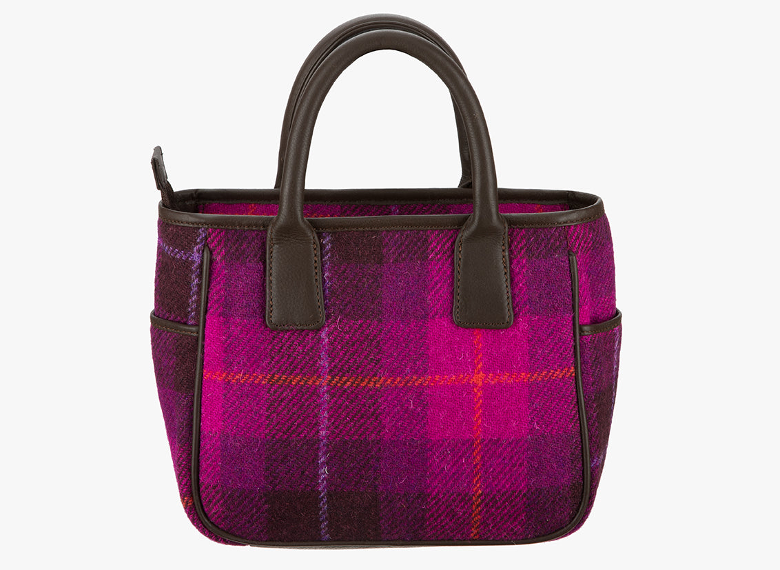 This is the reverse of the Harris Tweed handheld bag. This bag's colour is bright pink and dark pink check. It has a pocket on each side of the bag trimmed with brown leather.