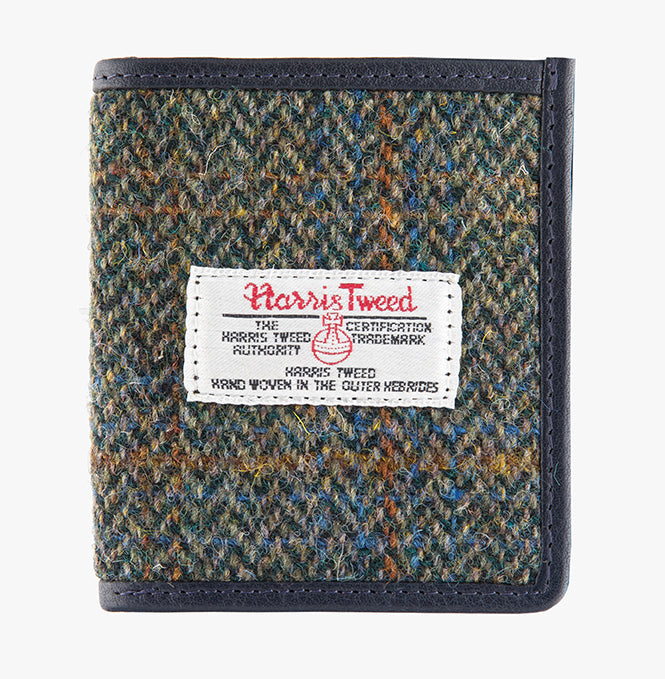 This is the front of the Harris Tweed card holder in blue and green, it is a blue and green small herringbone design with a blue, tan and orange overcheck.  It is trimmed in brown leather. This card and note holder has room for 6 cards and a slot to hold your banknotes. It has a rectangular Harris Tweed logo on the front.  