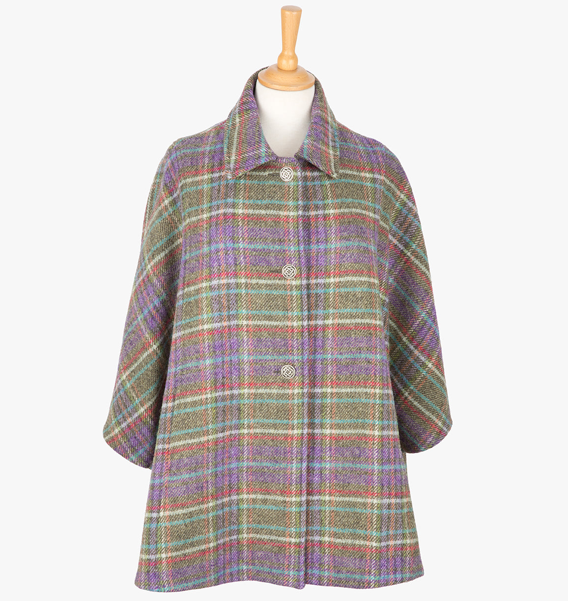 This is the Harris Tweed cape in Multi check, the colour is purple and  green with a white, red and turquoise overcheck. It has 3 buttons and a collar that can be worn both up and down. It has buttons at the side which hold the cape together to give it more structure. This cape has two pockets and is a one size fits all garment.