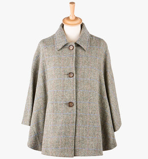 This is the Harris Tweed cape in Pastel check,  the colour is a beige and cream small herringbone with a blue and pink overcheck. It has 3 buttons and a collar which can be worn both up and down. It has buttons at the side which hold the cape together to give it more structure. This cape has two pockets and is a one size fits all garment.