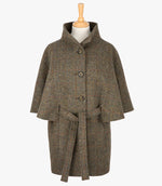 Harris Tweed belted cape in Brown herringbone. The cape has 4 buttons, a belt and a collar that can be worn up or folded down. It also has two pockets. It is a traditional cape style at the top but slightly more fitted through the hips. It has a stunning silky lining and comes in sizes small to large.