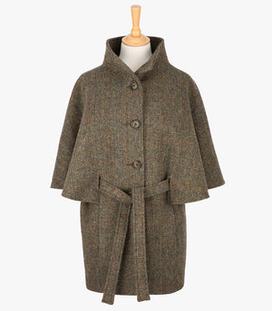 Harris Tweed belted cape in Brown herringbone. The cape has 4 buttons, a belt and a collar that can be worn up or folded down. It also has two pockets. It is a traditional cape style at the top but slightly more fitted through the hips. It has a stunning silky lining and comes in sizes small to large.