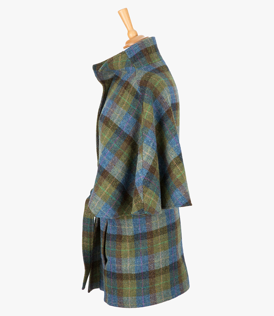 This is the side view of the belted cape in denim sage, the colour is blue, green and brown check. You can see the collar stood up and the sleeves of the cape which come mid-way down the arm. It has two pockets and ties at the waist for a neat silhouette.