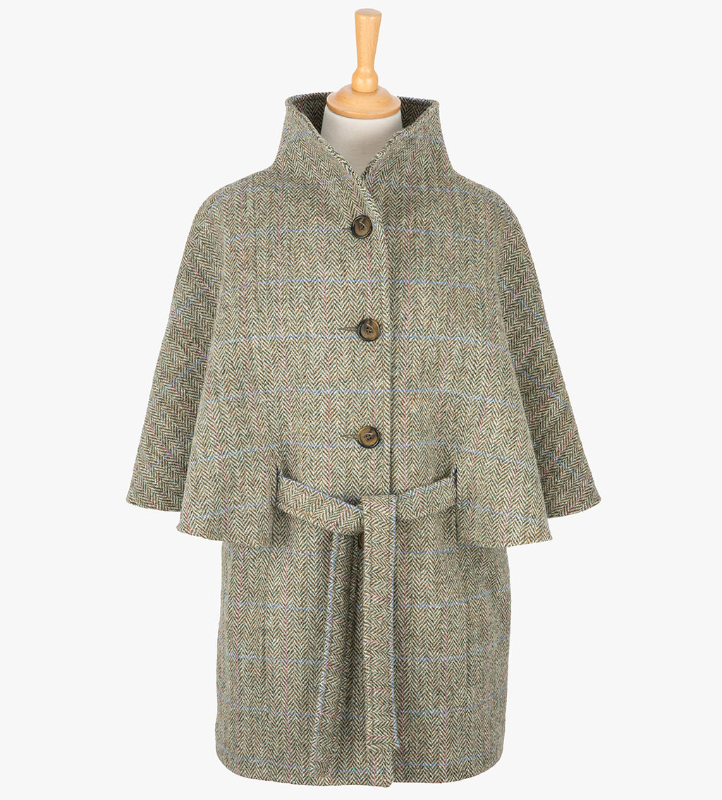 Harris Tweed belted cape in pastel check, the colour is cream and brown herringbone with a pink and blue overcheck. The cape has 4 buttons, a belt and a collar that can be worn up or folded down. It also has two pockets. It is a traditional cape style at the top but slightly more fitted through the hips. It has a stunning silky lining and comes in sizes small to large.