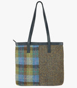 The reverse of this large Harris Tweed shopper with navy blue leather handles which can sit on the shoulder, it also has navy blue leather trim at the top of the bag. The bag design is in two halves, the left half is denim sage harris tweed this is green and blue check design, the right side is heath which is a brown and mustard small herringbone design.
