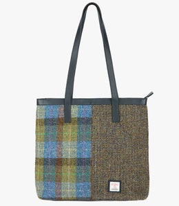 Large Harris Tweed shopper with navy blue leather handles which can sit on the shoulder it also has a navy blue leather trimat the top of the bag. The bag design is split in two with one half denim sage Harris Tweed, this is green and blue, the opposite side is heath which is a brown and mustard small herringbone design. It also has a small Harris Tweed logo on the front bottom right.