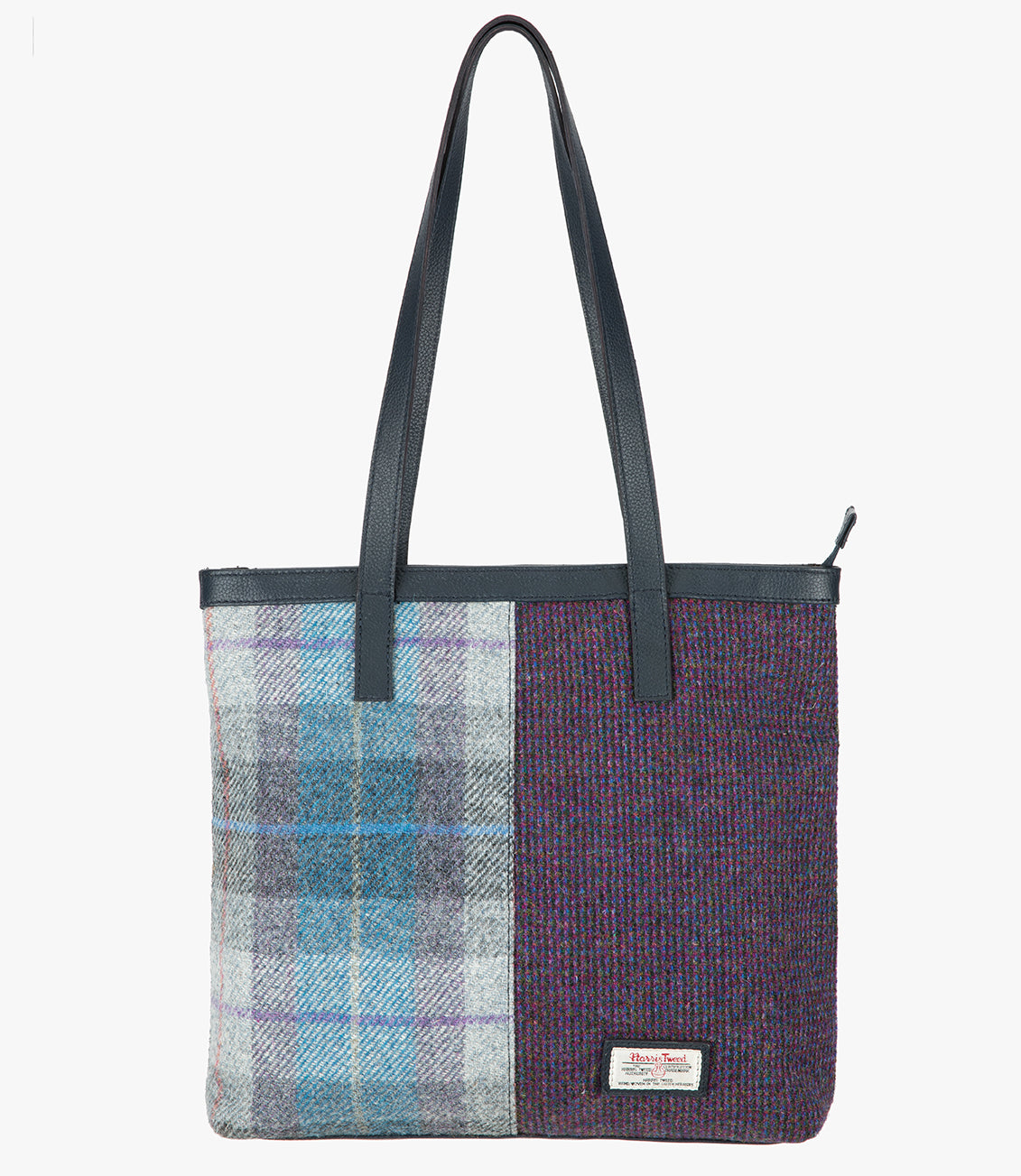 Harris Tweed shopper with a navy blue leather handle that sits comfortably on the shoulder. It also has a navy blue leather trim at the top of the bag. The bag design is in two halves, the left half is Lavender Harris Tweed, this is lilac, grey and blue check. The right side is a subtle purple and black check. It also has a small rectangular Harris Tweed logo at the bottom right.