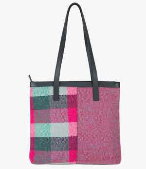 The reverse side of the Harris Tweed shopper with black leather handles that sit comfortably on the shoulder. It also has black leather trim around the top of the bag. The bag design is in two halves, the left half is a pink Harris Tweed check, which is bright pink, jade green, and light green check. The right side is a bright pink and pale blue herringbone