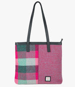 Harris Tweed shopper with a black leather handle that sits comfortably on the shoulder. It also has and black leather trim at the top of the bag. The bag design is in two halves, the left half is a pink and green check Harris Tweed, this is pink, jade green and light green check. The right side is a bright pink and pale blue herringbone design. It also has a small rectangular Harris Tweed logo at the bottom right.