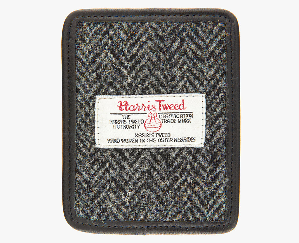 This is the front of the Harris Tweed card holder in charcoal herringbone, it is a grey and black herringbone design and is trimmed in black leather. This card and note holder has room for 3 cards. It has a rectangular Harris Tweed logo on the front.  