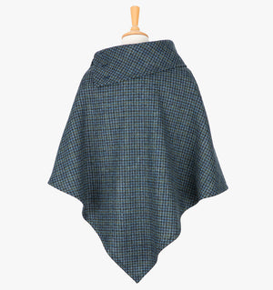 Rear view the poncho in mid-blue and black small houndstooth check. It drops over the head and drapes gently over the shoulders. It comes mid-way down the arms and finishes at a point at the back. It has a folded collar with 3 button holes on the left.