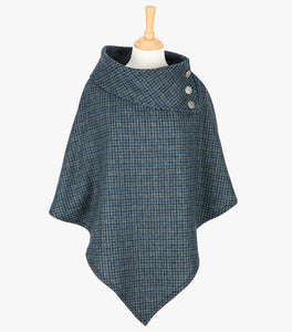 Tweed poncho in mid-blue and black small houndstooth check. It drops over the head and drapes gently over the shoulders. It comes mid-way down the arms and finishes at a point at the front. It has a folded collar with 3 Celtic buttons in silver on the right hand side.