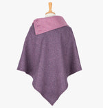 Rear view of the poncho in damson herringbone. It drops over the head and drapes gently over the shoulders. It comes mid-way down the arms and finishes at a point at the back. It has a contrasting folded collar in light pink with 3 button holes on the left.