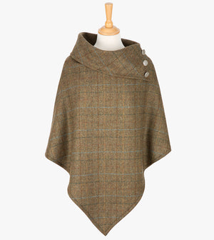 Tweed poncho in Earth, this poncho drops over the head and drapes gently over the shoulders. The colour is brown with a black, brown and blue overcheck. It comes mid-way down the arms and finishes at a point at the front. The poncho has a folded collar with 3 Celtic buttons in silver on the right hand side.