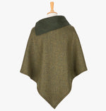 Rear view of the forest green poncho which drops over the head and drapes gently over the shoulders. It comes mid-way down the arms and finishes at a point at the back. The colour is forest green herringbone with a contrasting folded collar in dark green with 3 button holes on the left.