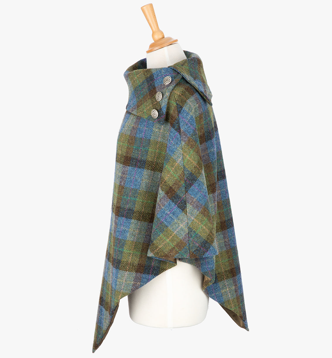 Side view the poncho in Denim Sage check. It drops over the head and drapes gently over the shoulders. It comes mid-way down the arms and finishes at a point at the front. The colour is blue, green and brown check. It has a folded collar with 3 Celtic buttons in silver.