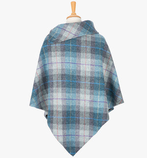 Rear view of the Lavender poncho, this drops over the head and drapes gently over the shoulders. It comes mid-way down the arms and finishes at a point at the back. The colour is a blue and grey check. It has a folded collar with 3 button holes on the left.