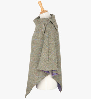 Side view the poncho in pastel check. It drops over the head and drapes gently over the shoulders. It comes mid-way down the arms and finishes at a point at the front. The colour is a neutral brown with a blue and pink overcheck. It has a folded collar with 3 Celtic buttons in silver.