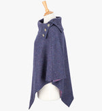 Side view the poncho in Violet. It drops over the head and drapes gently over the shoulders. It comes mid-way down the arms and finishes at a point at the front. The colour is purple. It has a folded collar with 3 Celtic buttons in silver.
