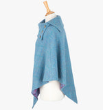 Side view the poncho in Sky. It drops over the head and drapes gently over the shoulders. It comes mid-way down the arms and finishes at a point at the front. The colour is Sky blue. It has a folded collar with 3 Celtic buttons in silver.