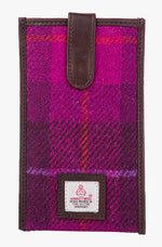 Harris Tweed phone case in cerise check trimmed with leather. This case has a magnetic closing and a small Harris Tweed logo at the bottom of the case.