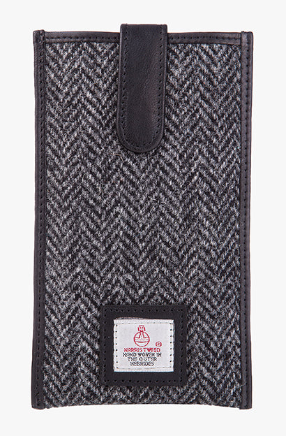 Harris Tweed phone case in charcoal herringbone, trimmed with leather. This case has a magnetic closing and a small Harris Tweed logo at the bottom of the case.